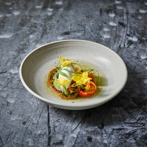 Verfijnd gerecht met groenten en eetbare bloemen, geserveerd in een kom