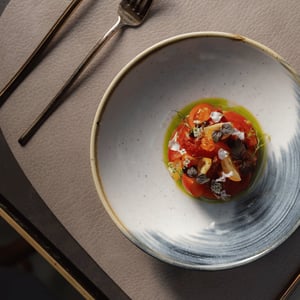 Een verfijnd tomatengerecht met kruiden en eetbare bloemen.