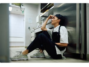 Exhausted chef sitting on the kitchen floor after a stressful service