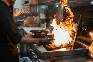 Chef cooking over an open flame during busy restaurant service