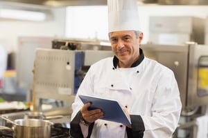 Professional chef reviewing kitchen operations on a tablet